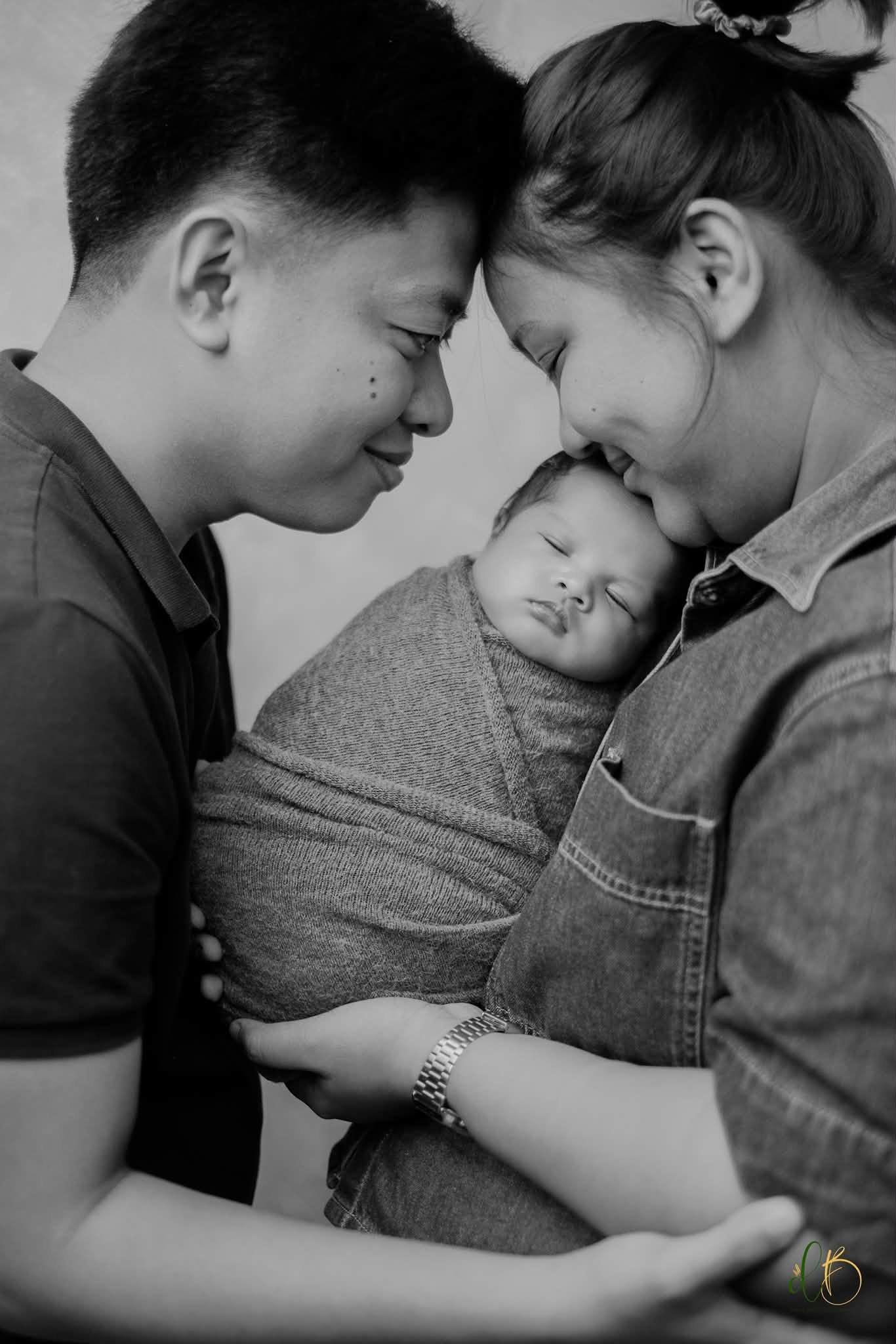 Parents sharing a tender moment with their newborn during a Newborn Mini Plus You session