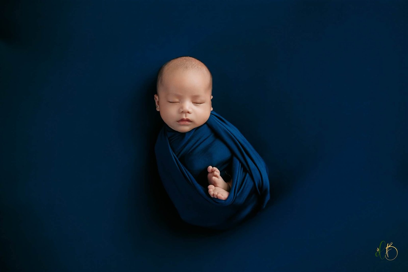 Newborn wrapped in deep blue fabric